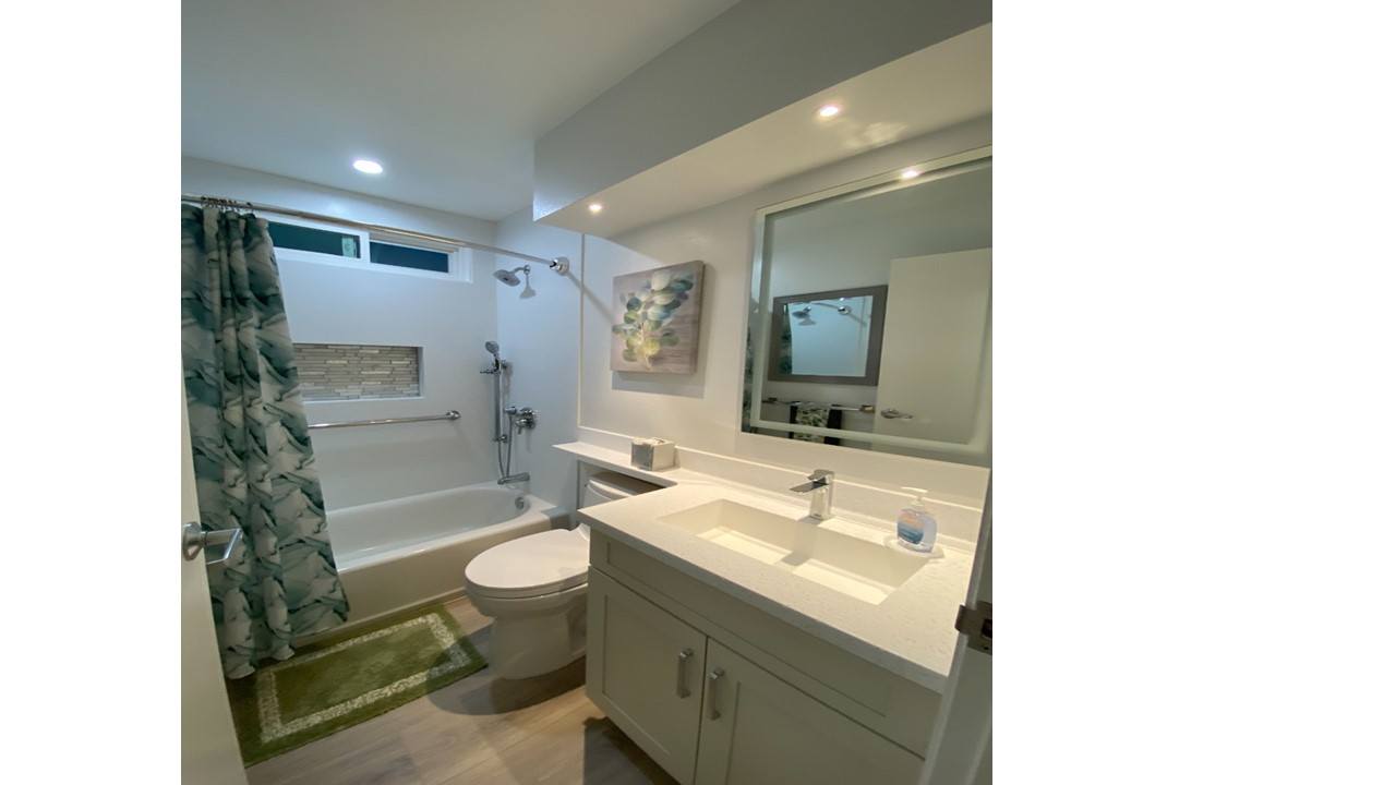 A bathroom with a toilet, sink, and mirror.